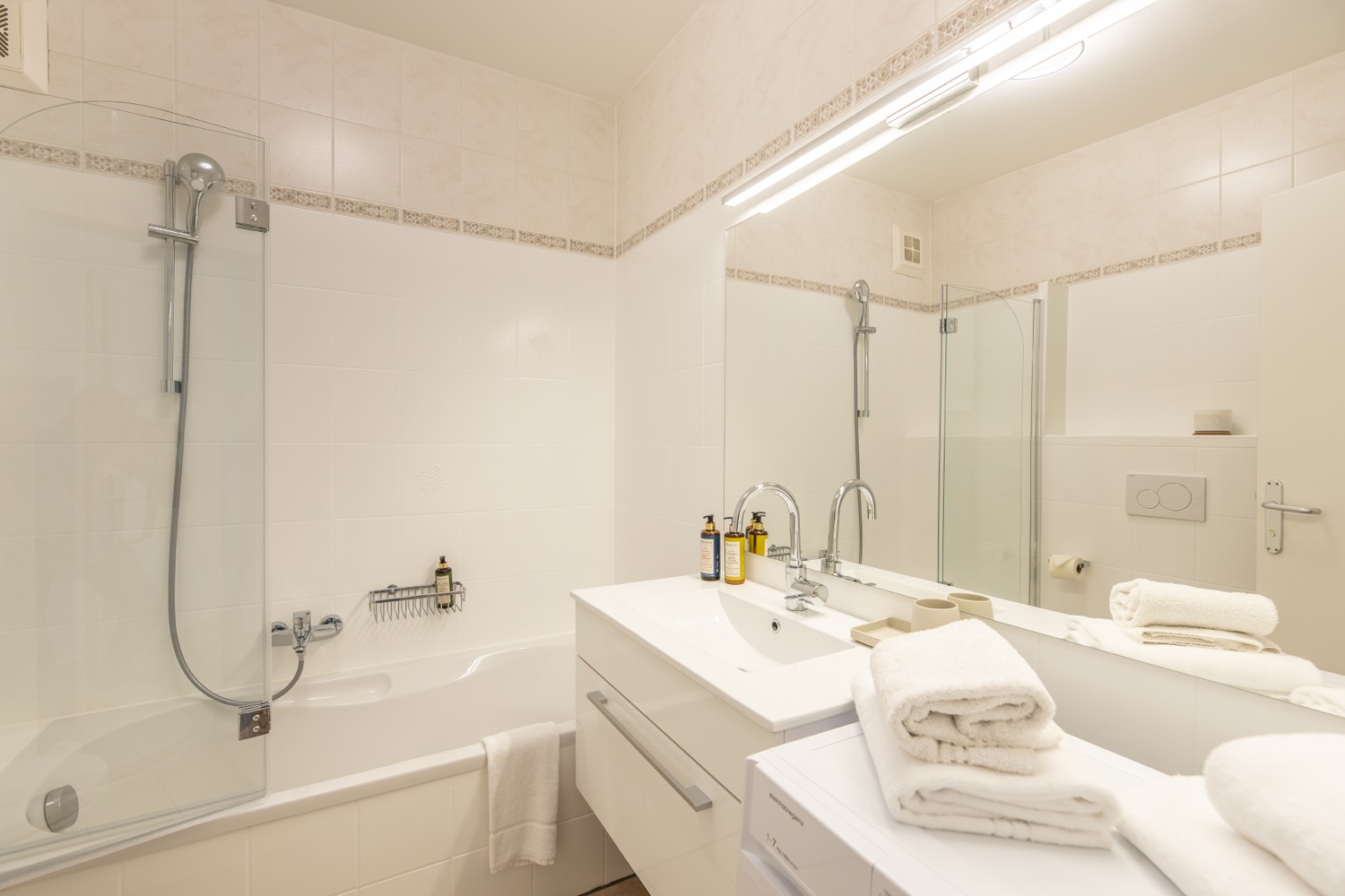 Helles Badezimmer mit Badewanne, Waschtisch und großem Spiegel